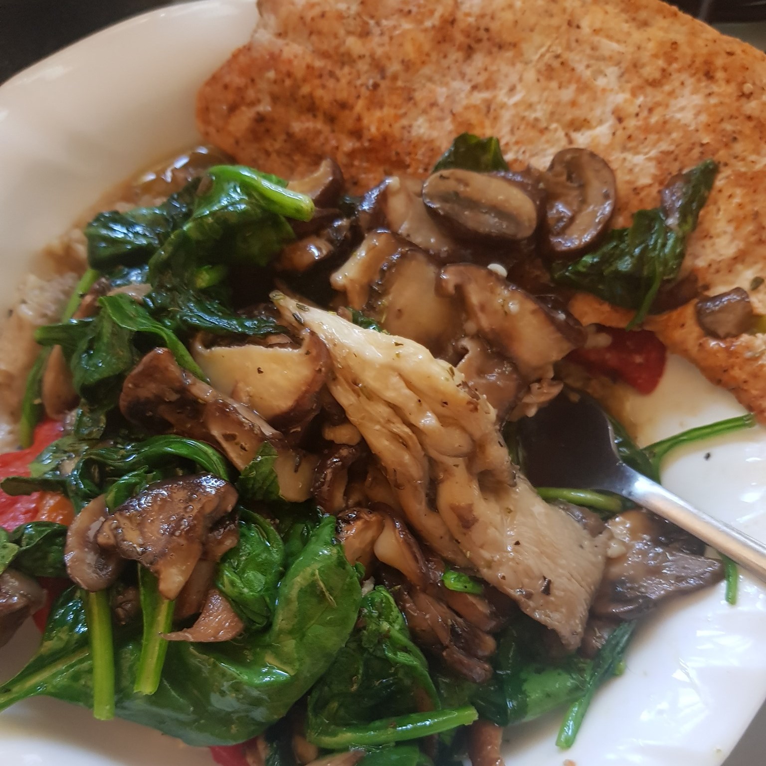 bowl of savory oatmeal topped with sauteed spinach, mushrooms, and roast salmon